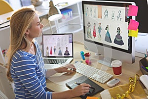 Female fashion designer using graphic tablet while working at desk