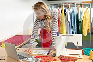 Female fashion designer using laptop at desk
