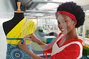 Female fashion designer using measuring tape on a mannequin in design studio