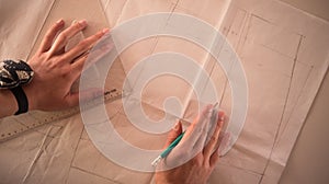 Female fashion designer working with pattern cutting at studio, top view.