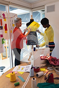 Female fashion designers using measuring tape on a mannequin