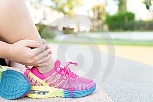 Female fatty runner athlete leg injury and pain. Hands grab painful leg while running in the park