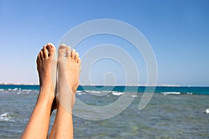 Female feet against the sea