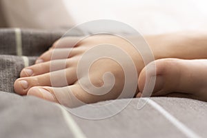 Female feet in bed. The bed is gray, pink, soft pastel colors.