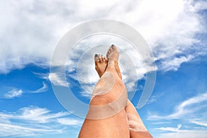 Female feet with blue nails with the summer sky in the background in Bornholm island, Denmark