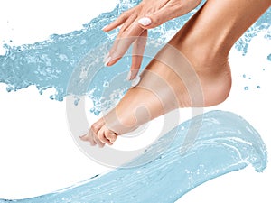 Female feet with cream among water splashes.