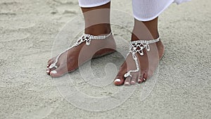 Female feet and fingers on sand in summer. Beautiful woman feet on sand.The legs of a black young woman are decorated for the wedd