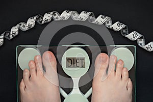 female Feet on floor scales, body weight control, the word DIET on the dial of the scales
