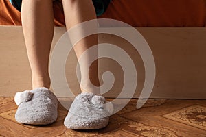 Female feet in home gray slippers on the cold floor