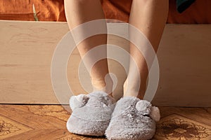 Female feet in home gray slippers on the cold floor