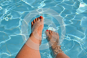 Female feet, legs in swimming pool