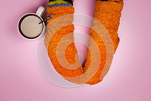 Female feet in orange socks on a pink background