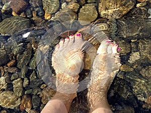 Female feet with painted nails in clear water. Fetish