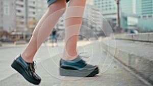 Female feet in patent platform shoes making steps to climb up stairs outdoors