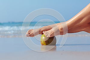 Female feet propped on coconut on sea background