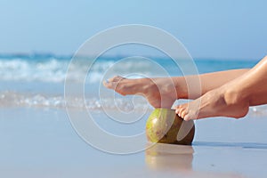 Female feet propped on coconut on sea background photo