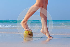 Female feet propped on coconut on sea background photo