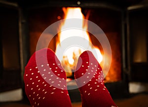 Female feet in red woolen socks by a warm fireplace on a cold winters evening