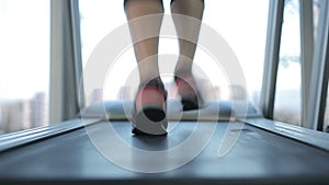 Female feet running fast on treadmill, working hard to succeed and reach goal