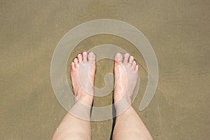 Female feet on sand.