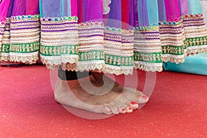 Female feet in a sari standing on a red carpet during wedding ceremony