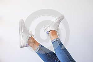 Female feet in sneakers raised up. Isolated on white background