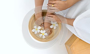 Female feet soaked in a bowl filled with water and flower petals, a depiction of relaxation and luxurious self-care