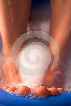 Female feet in soap bath