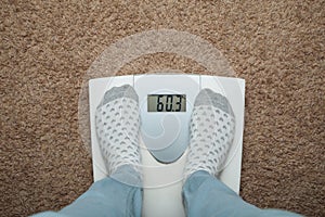 Female feet in socks on electronic scales. Excess weight and diet