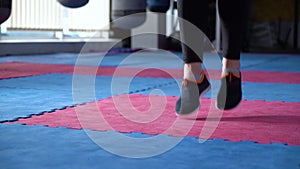 Female feet in sports shoes skipping on rope in gym