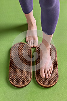 Female feet stand on a sadhu board with nails, on a green mat, yoga practice, close up