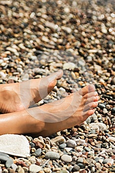 Female feet during sunny day at the pebbly beach