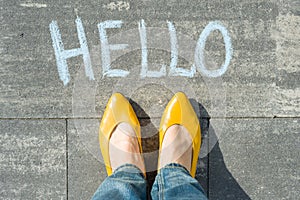 Female feet with text hello written on asphalt