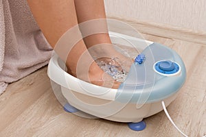 Female feet in a vibrating foot massager. Electric massage foot bath. Pedicure and foot care.