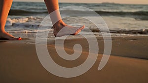 Female feet walking barefoot on sea shore.