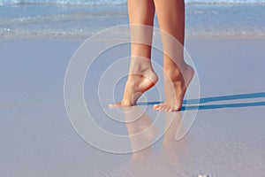 Female feet in water on the beach