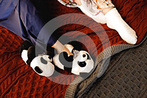 Female feet wearing cozy warm wool socks, panda Slippers close up