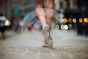 Female feet wearing sneakers running in city street. Woman with beautiful legs running in city at morning