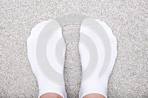 Female feet wearing white cotton socks on a carpet, rug at home, casual comfortable style at home n winter