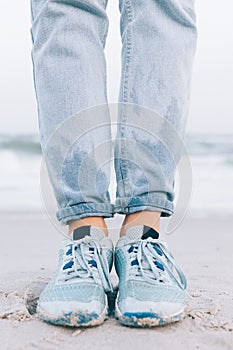 Female feet in wet sneakers and jeans