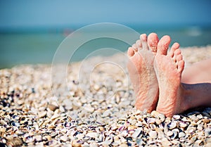 Female feet on white shell beach