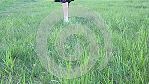 Female feet in white sneakers run on the grass to the camera.