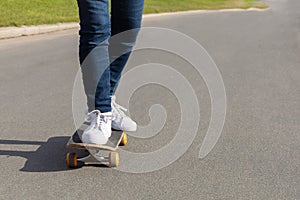 female feet in white sneakers on skateboard on asphalt, on track. woman legs on board at skatepark.