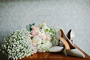 Female feet in white wedding sandals with a bouquet of camomiles