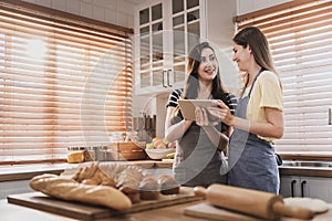 Female and female or LGBT couples are happily cooking bread together in the home kitchen