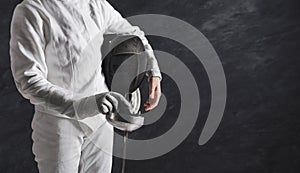 Female fencer in white fencing suit at black background