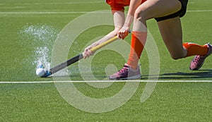 Female field hockey player passing to a team mate on a modern, water artificial astroturf field photo