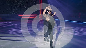 Female figure skater moves to camera in arabesque,beautifully stretching arm forward and making graceful movements with