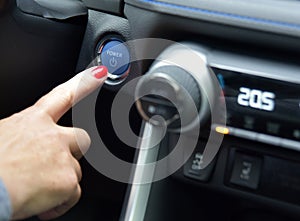 Female finger on the button to activate car engine