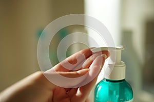 A female finger presses on a disinfectant gel in a small plastic